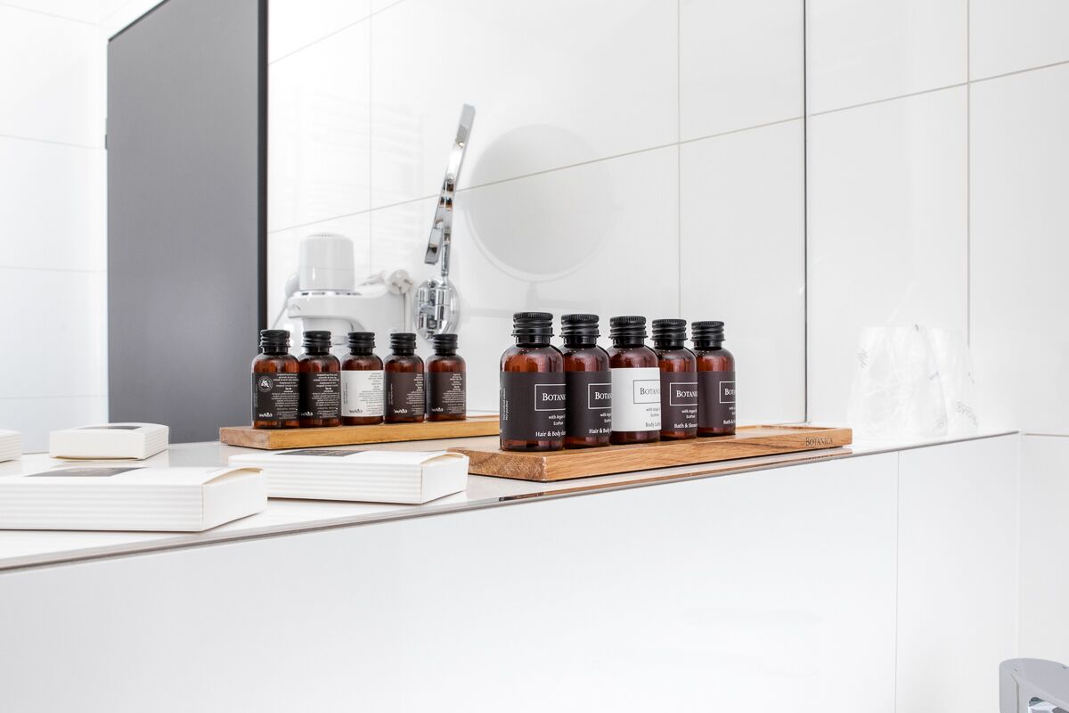 Une salle de bain avec un miroir, un lavabo et une étagère sur laquelle se trouvent plusieurs flacons de produits capillaires.