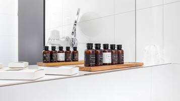 A bathroom with a mirror, a sink, and a shelf with several bottles of hair care products.