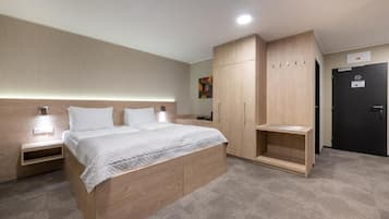 Un dormitorio moderno con una cama de madera, mesitas de noche, un armario y una puerta con un cartel.