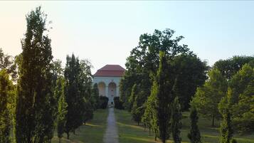 A pathway leading to a building with a red roof, surrounded by trees.