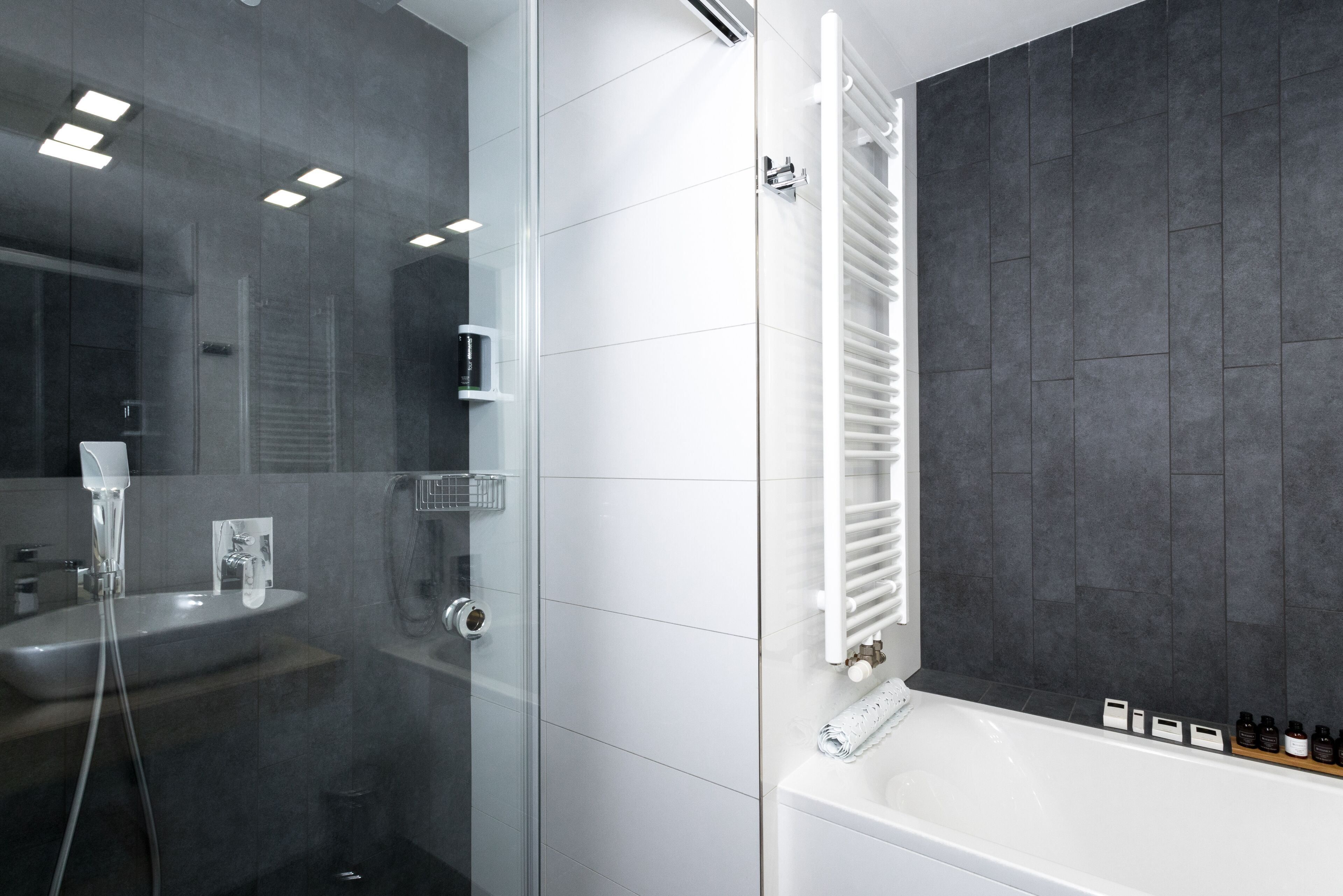 A modern bathroom with a glass-enclosed shower, a white sink, and a bathtub with a towel rack.