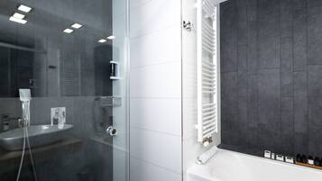 A modern bathroom with a glass-enclosed shower, a white sink, and a bathtub with a towel rack.