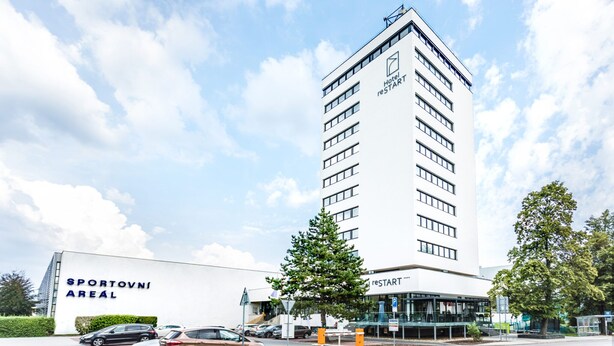 Un edificio de hotel alto con un letrero que dice "Hotel restart" y un estacionamiento con coches.
