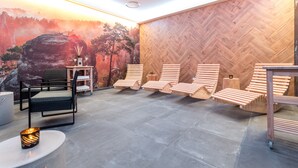 Un área de spa con tumbonas de madera, una mesa de masaje y un mural en la pared.