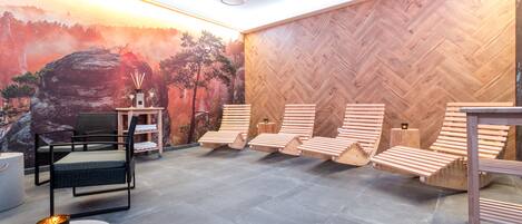 Un área de spa con tumbonas de madera, una mesa de masaje y un mural en la pared.