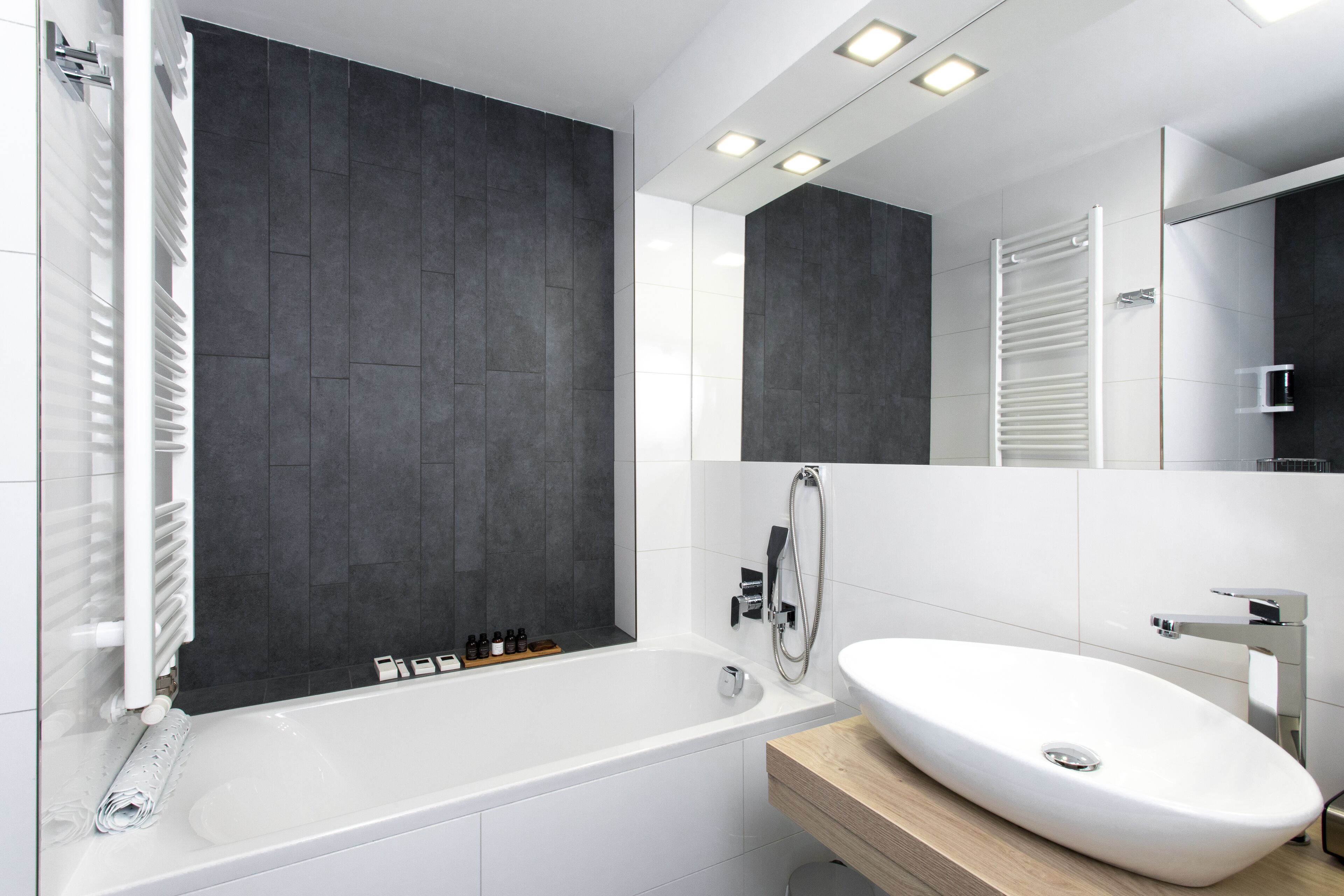 Un baño moderno con bañera, lavamanos blanco y un espejo grande.