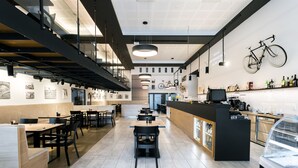 Un interior de restaurante moderno con una zona de bar, asientos y una vitrina.
