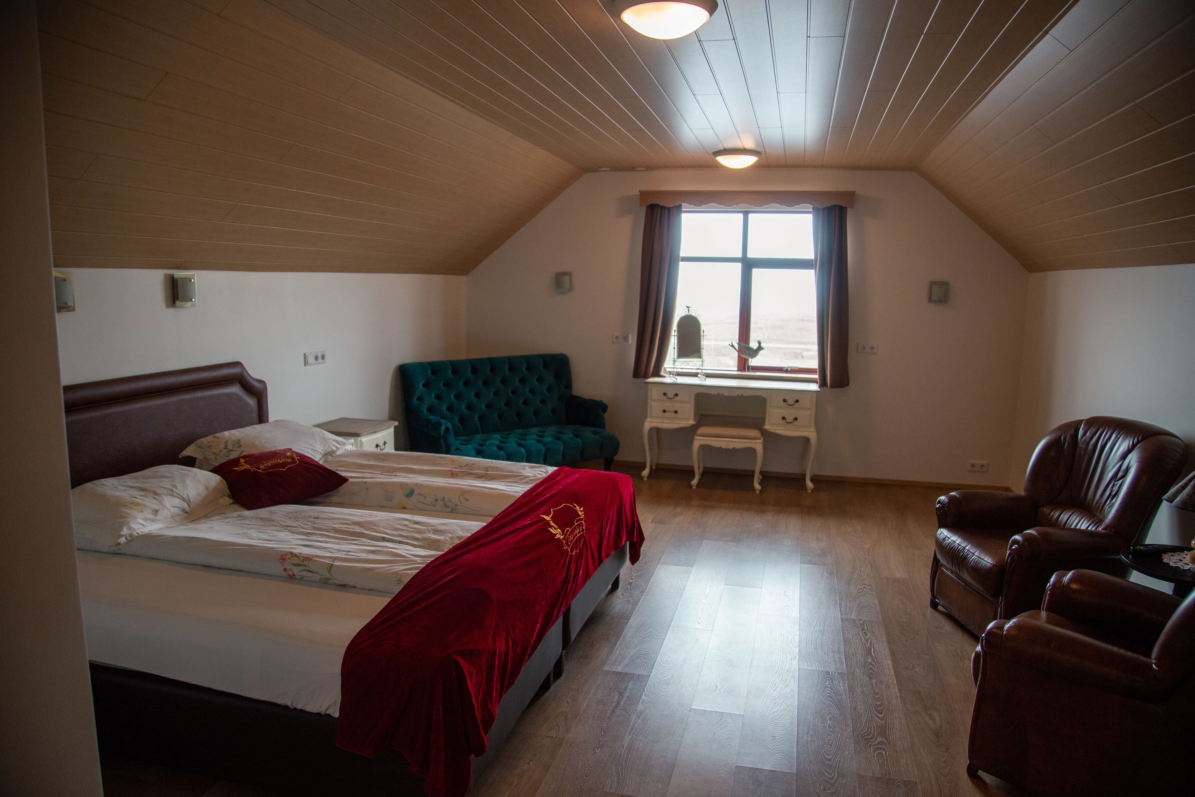A bedroom with a bed, a desk, a chair, and a window.