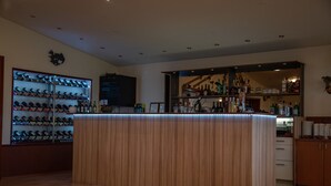 A bar area with a wine rack, shelves with bottles, and a counter. - Hotel Smyrlabjorg (Höfn)