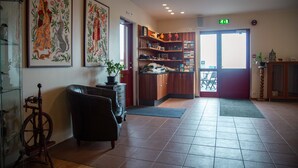 A hotel lobby with a leather armchair, a wooden cabinet, and a bookshelf. - Hotel Smyrlabjorg (Höfn)