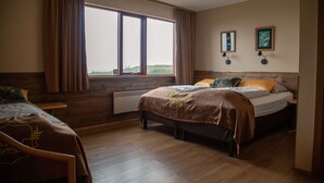 A hotel room with two beds, a large window, wooden flooring, and a view of the outdoors. - Hotel Smyrlabjorg (Höfn)