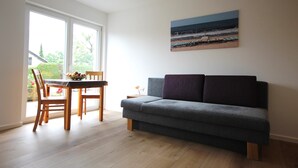 Ein Wohnzimmer mit einer Couch, einem Esstisch mit Stühlen und einem Bild an der Wand.