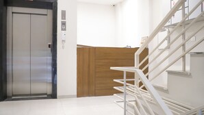 A modern elevator, a wooden panel wall, and a white staircase. - Itsy Hotels Kamron (Mohali)