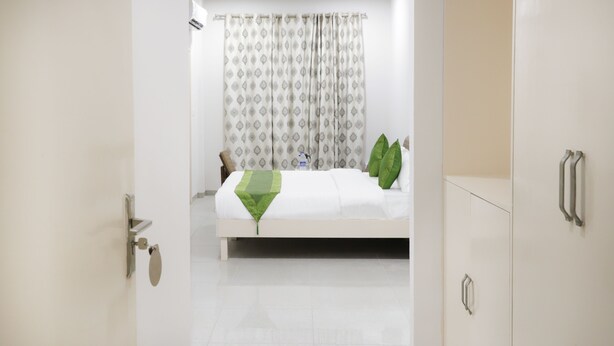 A hotel room with a bed, a bathroom door, and a wardrobe. - Itsy Hotels Kamron (Mohali)