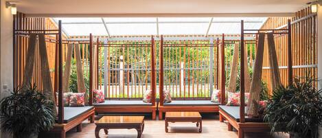 A pool area with wooden benches and a red pool table, surrounded by potted plants and a wooden fence.