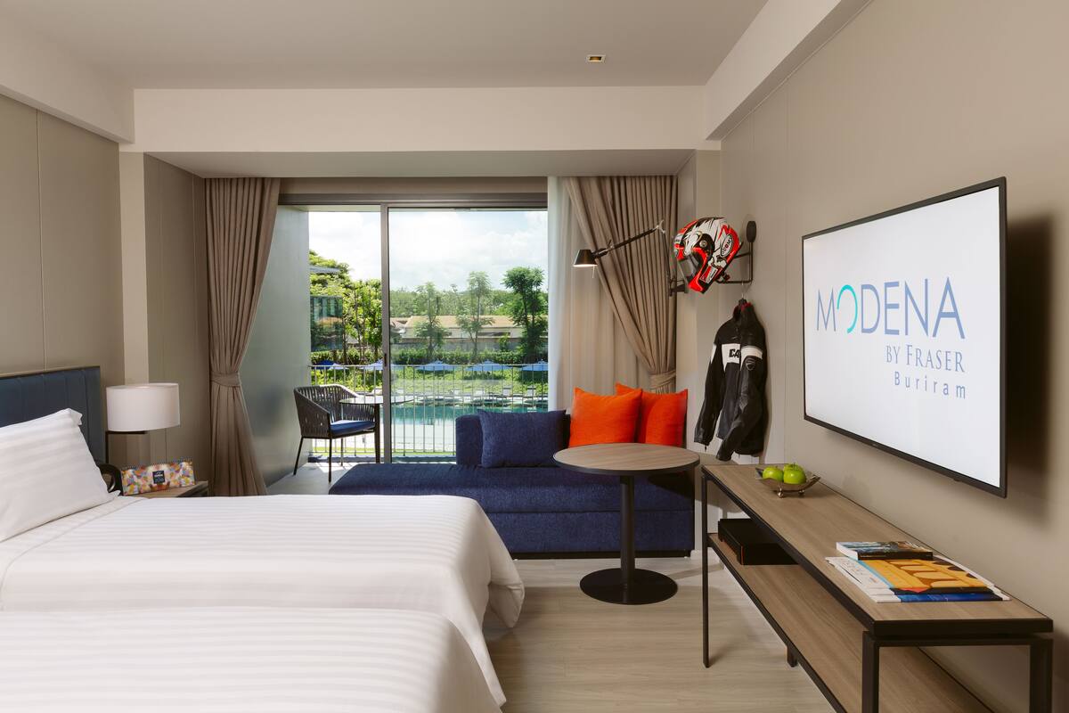 Ein Hotelzimmer mit Bett, Schreibtisch, Stuhl, Fernseher und Blick ins Freie.