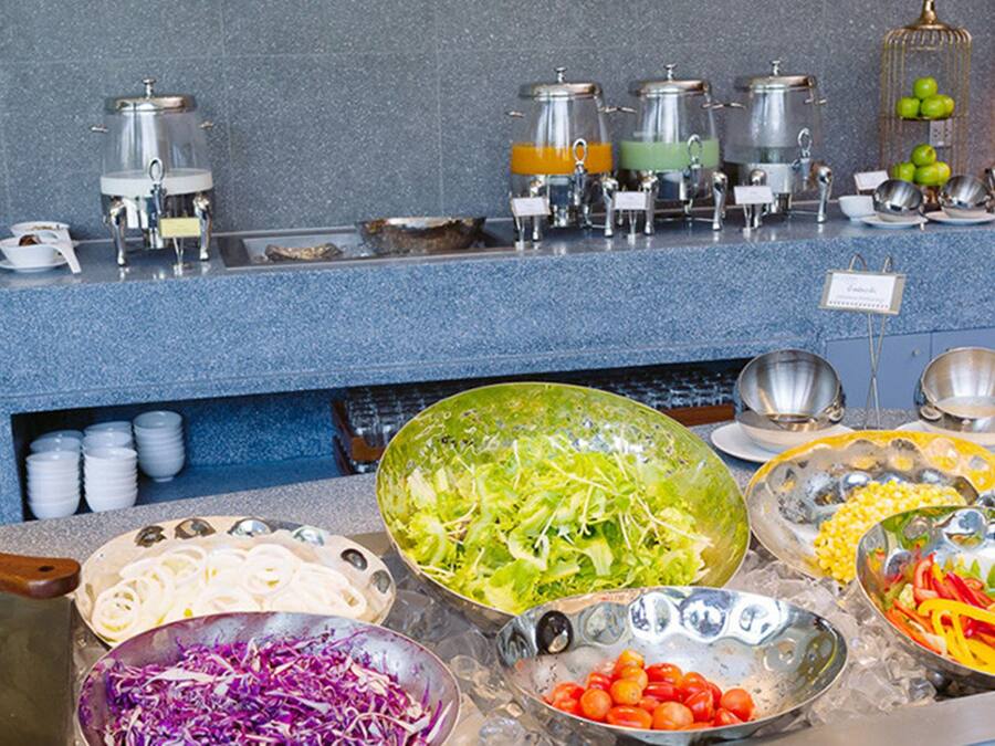 Un bufé con diferentes opciones de comida, incluyendo queso, ensaladas y frutas.