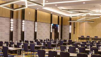 A conference room with rows of tables and chairs, equipped with water bottles and glasses.