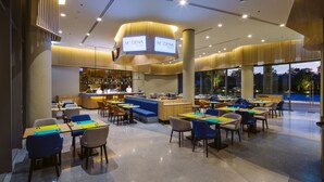Un restaurante moderno con una zona de bar, diferentes disposiciones de asientos y un letrero grande iluminado.
