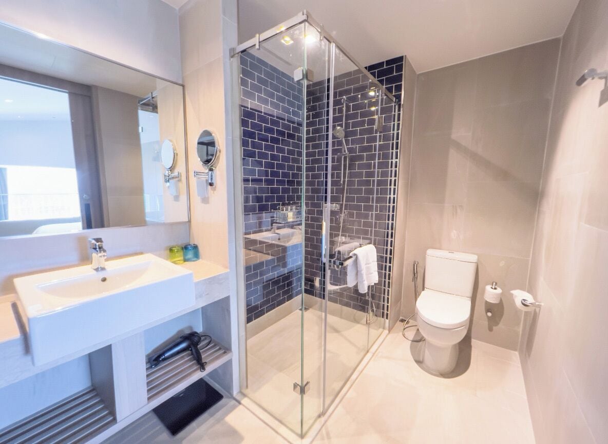 A modern bathroom with a glass-enclosed shower, a white sink, and a toilet.