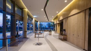 Un vestíbulo amplio con techos altos, ventanas grandes y mobiliario moderno.