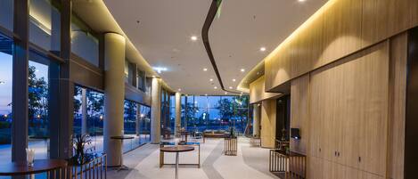 A spacious lobby with high ceilings, large windows, and modern furniture.
