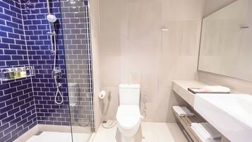 Un baño con ducha de vidrio, inodoro blanco y un espejo grande sobre el lavamanos.