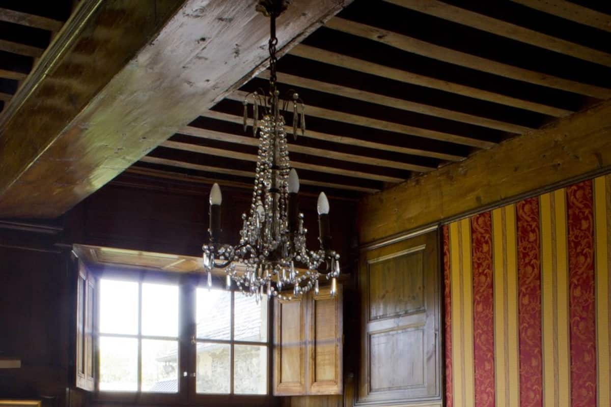 A traditional bedroom with a wooden bed, a chandelier, and large windows.