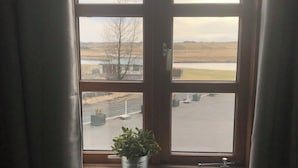 A window with a view of a parking lot and fields.