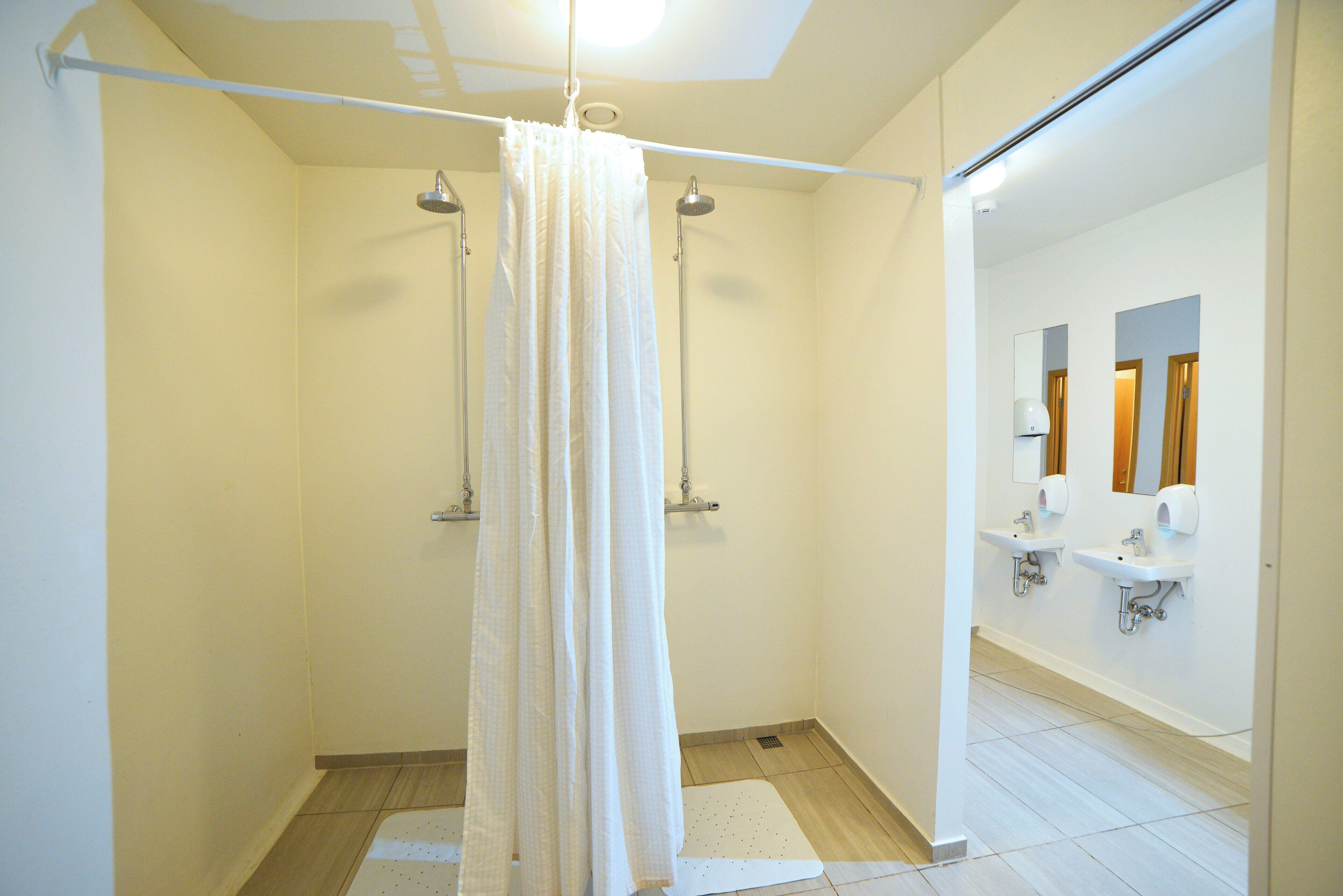 A modern bathroom with a shower, two sinks, and a mirror.