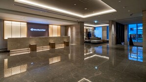 Un hall d’hôtel moderne comprenant un comptoir d’accueil, un espace salon et une vue sur l’extérieur.