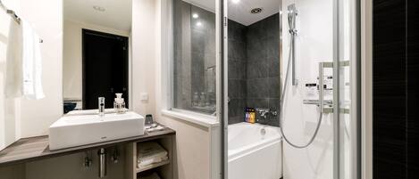 A modern bathroom with a large mirror, a sink, a bathtub, and a shower.
