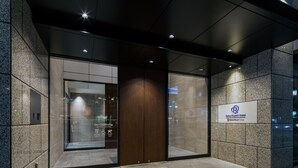 L’entrée d’un hôtel au design moderne, avec une porte en verre, une porte en bois et une enseigne indiquant qu’il fait partie du groupe hôtelier Dolfyn Resort.