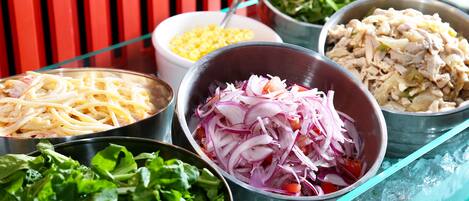 A variety of food items on a table, including pasta, shredded chicken, and mixed vegetables.