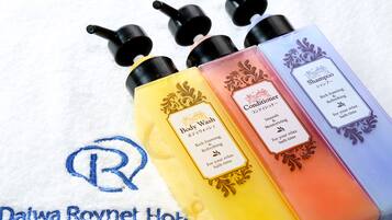 Four bottles of body wash and conditioner with labels, placed on a towel with a logo.
