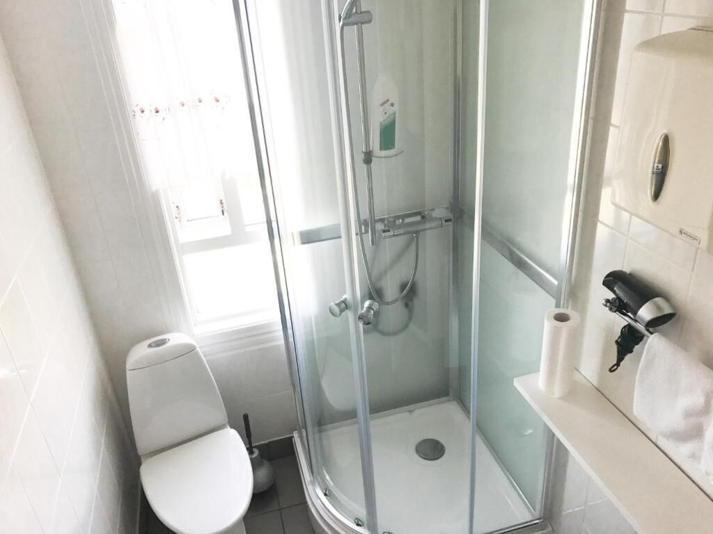 Une salle de bain avec une douche à parois de verre, des toilettes et un lavabo équipé d’un porte-serviettes.