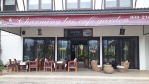A cafe with outdoor seating and a sign reading "Charming Lao Cafe Garden". - Charming Lao Hotel (Oudomxay)