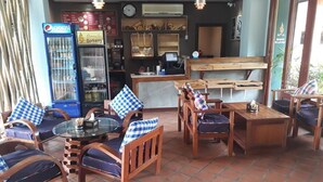 A restaurant with wooden furniture, a glass table, and a Pepsi vending machine. - Charming Lao Hotel (Oudomxay)