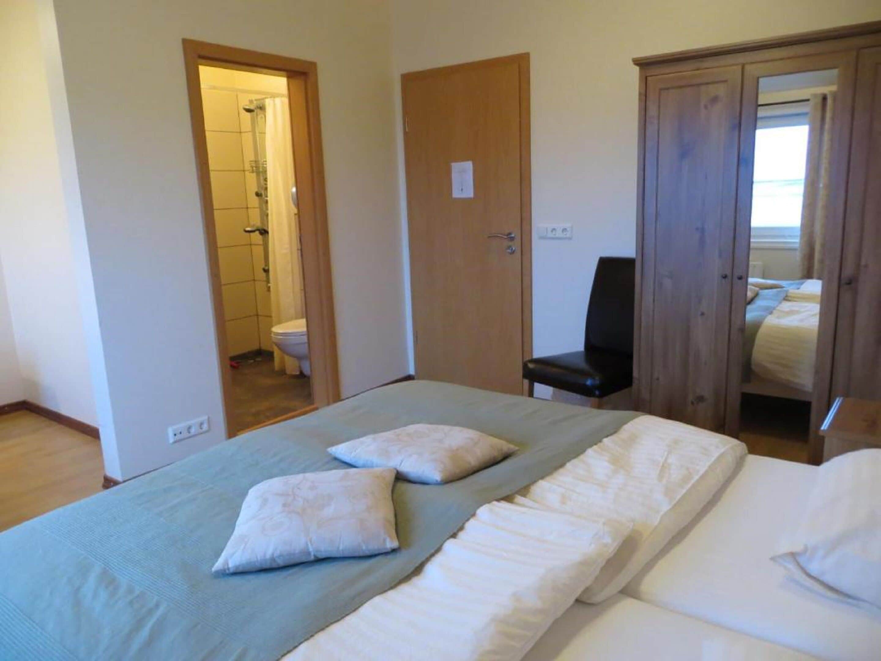 Une chambre à coucher avec un lit, deux oreillers, une chaise et une armoire.