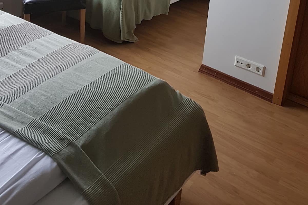 A room with two beds, a chair, and a window.