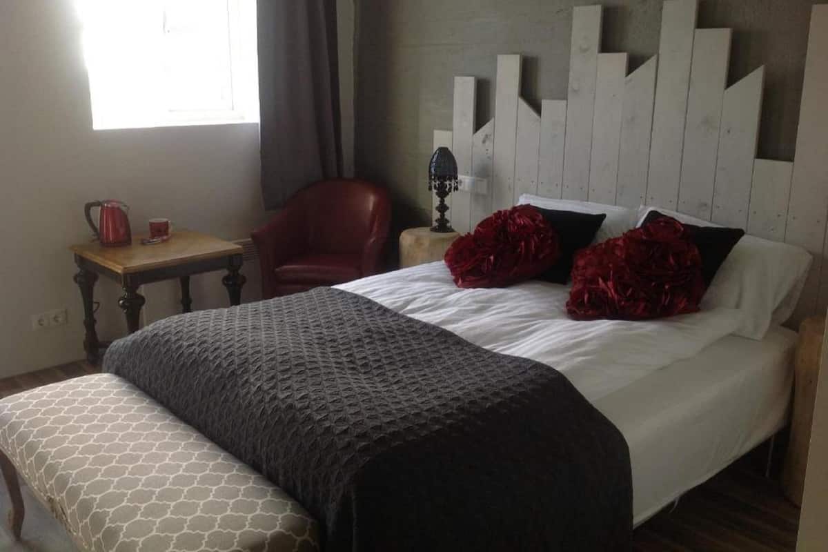 A bedroom with a bed, a chair, a table, and a lamp.