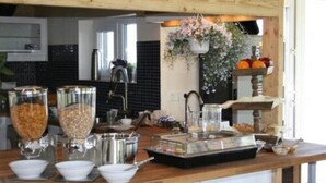 Una encimera de cocina con diversos alimentos y recipientes, una cesta de flores colgante y una presentación de frutas.