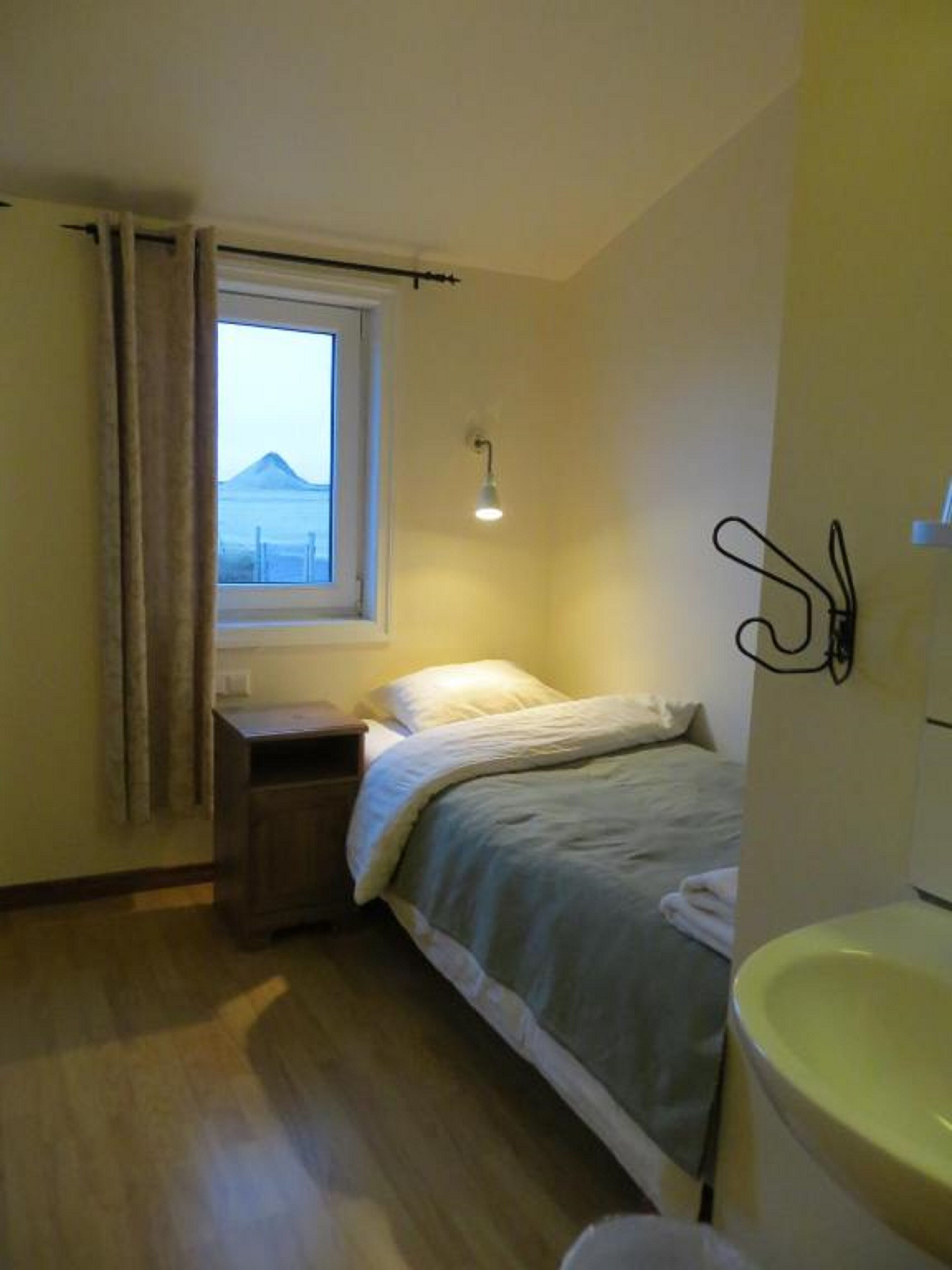 Ein Schlafzimmer mit Bett, einem Fenster mit Bergblick, einem Nachttisch und einer Wandleuchte.