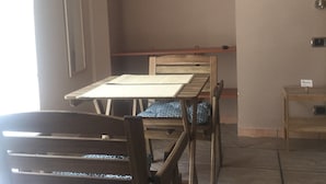 A room with a wooden dining table and chairs, a small wooden shelf, and a clothes drying rack against the wall. - Naples to live (Naples)