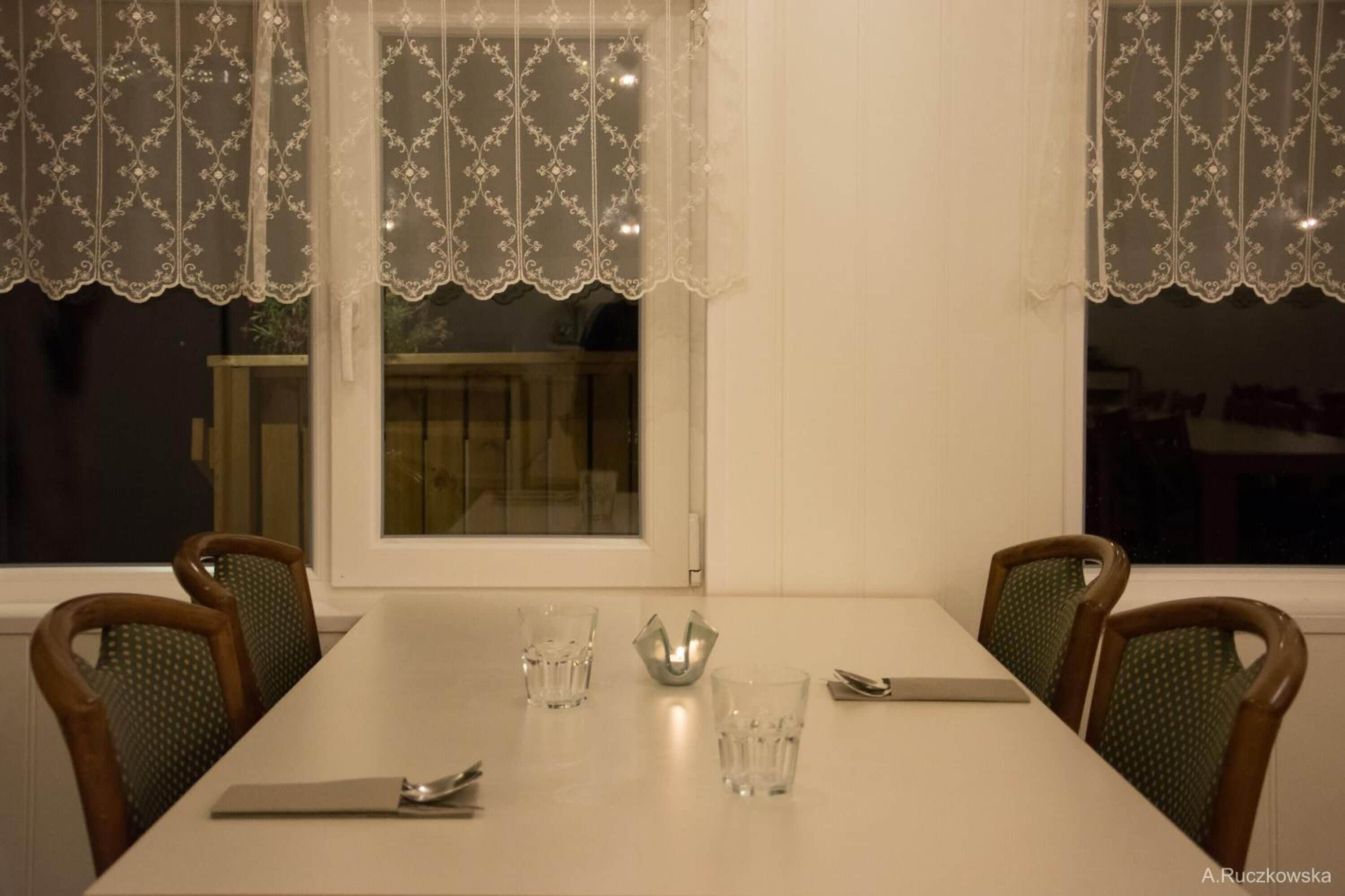 Une table à manger avec quatre chaises, un service de couverts et deux verres.
