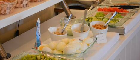 A buffet with various food items including fruits, vegetables, and bowls of food.