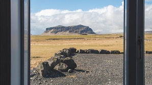Une vue sur une montagne, prise à travers une fenêtre, avec un paysage rocheux au premier plan.