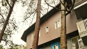 A multi-story building with a grey facade, white window frames, and a white picket fence. - 87 Guesthouse (Baguio)