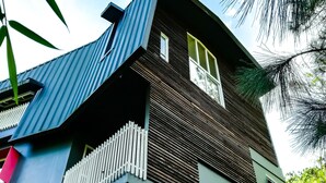 A modern two-story building with a sloped roof, a balcony with a white railing, and a small window on the upper floor. - 87 Guesthouse (Baguio)