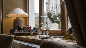 A cozy seating area with a lamp, decorative pine cones, and glassware on a windowsill. - La Couronne (Jougne)